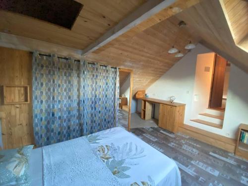 a bedroom with a bed and a wooden ceiling at La maison paisible in Guéméné-Penfao