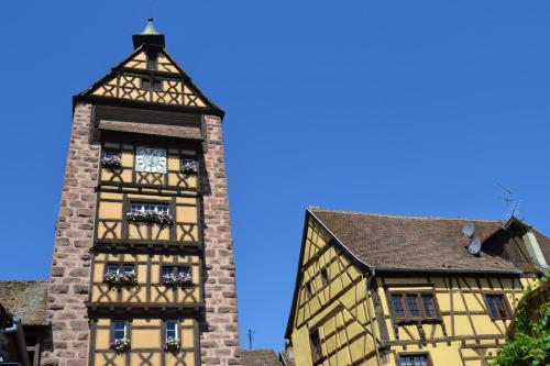 a tall brick building with a clock tower at Hôtel le Saint Nicolas in Riquewihr