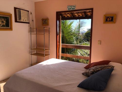 a bedroom with a bed and a large window at Excelente casa Búzios/Geribá in Búzios