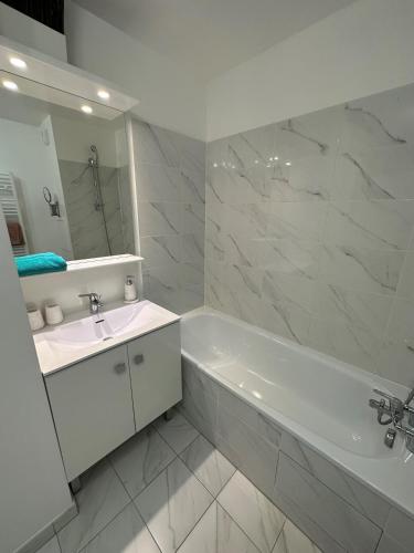 une salle de bain blanche avec une baignoire et un lavabo dans l'établissement Superbe appart au pied de disney, à Serris