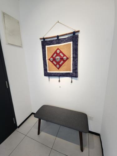 a bench in a room with a quilt hanging on a wall at Executive Premium Urban Suites - Jelutong in Jelutong