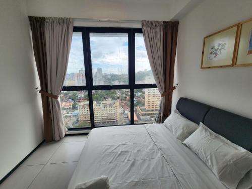 a bedroom with a bed and a large window at Executive Premium Urban Suites - Jelutong in Jelutong