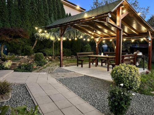 a wooden pergola with a picnic table in a garden at Útulný malý domček s vírivkou in Košice