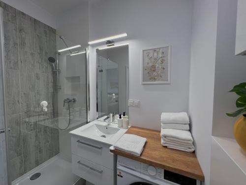 a white bathroom with a sink and a shower at Studio Apartment Honey by Galeria Północna in Warsaw