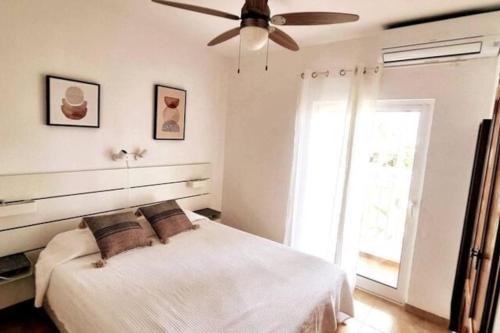 - une chambre avec un lit et un ventilateur de plafond dans l'établissement Adosado en Urbanización la Aldea Denia, à Dénia