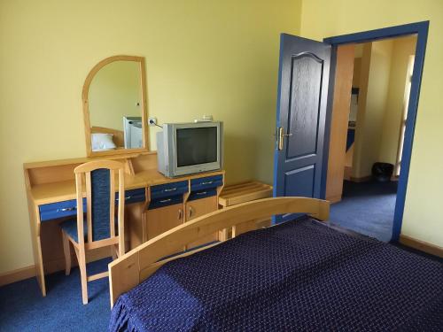 a bedroom with a desk with a tv and a mirror at Garni Lupus prenoćište in Kanjiža