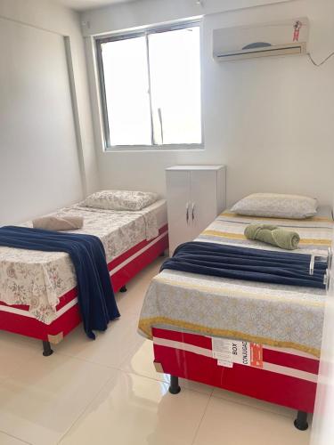 a bedroom with two beds and a window at Apto Garagem Wifi Condomínio Piscina Ar-condicionado 2 Quartos in Petrolina