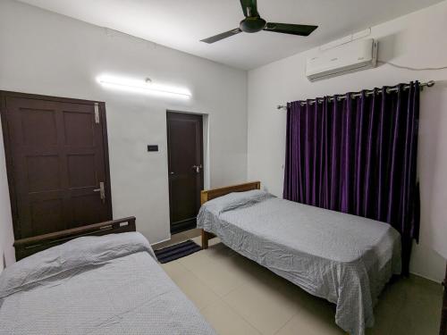 a bedroom with two beds and a ceiling fan at Budget Home in Cochin