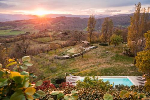 a villa with a pool on a hill with the sunset at Nikis Resort in Gubbio