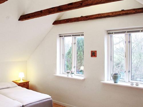 sypialnia z 3 oknami i łóżkiem w pokoju w obiekcie Holiday home Holeby w mieście Holeby
