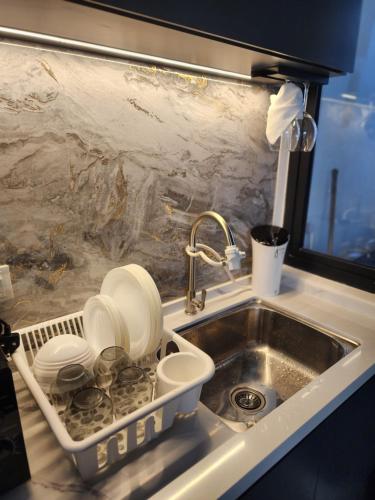 a sink with dishes in a dish drying rack next to it at Executive Premium Urban Suites - Jelutong in Jelutong
