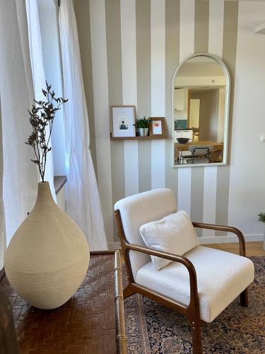 een woonkamer met een vaas, een stoel en een spiegel bij Le Pistachier - Maison cozy avec jardin privatif in Saint-Jean-de-Védas