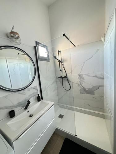 une salle de bain blanche avec un lavabo et une douche dans l'établissement Appartement de charme aperçu mer, à Fréjus