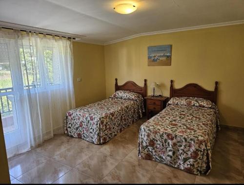 1 dormitorio con 2 camas y ventana en Apartamentos A Gàndara, en O Grove