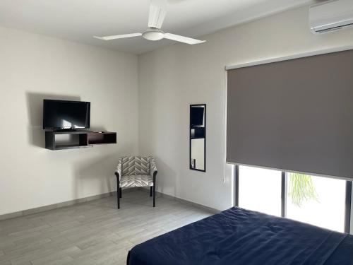 a bedroom with a bed and a tv and a chair at Excelente Departamento en planta baja colonia Altabrisa in Mérida