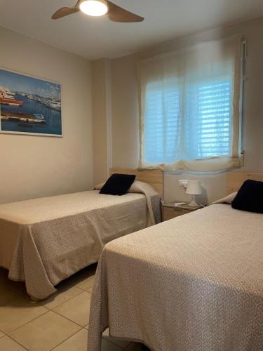 オリーバにあるApartamento Vora Golf Olivaのベッドルーム1室(ベッド2台、窓付)