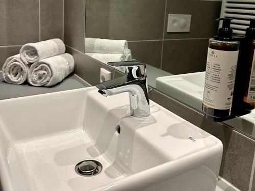 a bathroom sink with a faucet and some towels at Apartimo München-Unterhaching in Unterhaching
