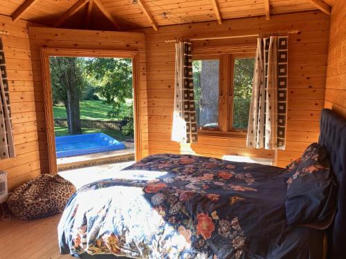 ein Schlafzimmer mit einem Bett in einem Blockhaus in der Unterkunft Exclusive 1 or 2 Bedroom Apartment with Summer House and Hot Tub in Daventry