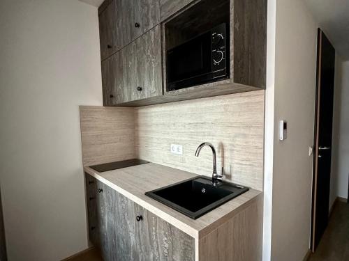 a kitchen with a sink and a microwave at Apartimo München-Unterhaching in Unterhaching