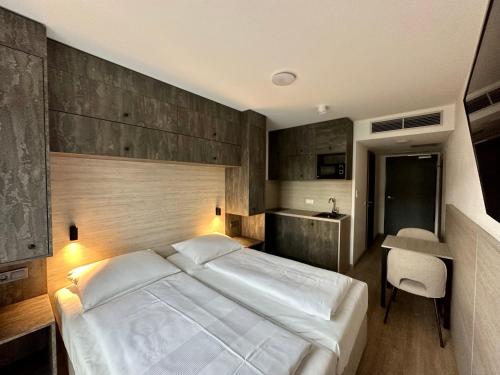 a bedroom with a large white bed and a desk at Apartimo München-Unterhaching in Unterhaching