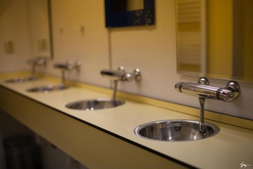 a row of three sinks in a public bathroom at Groepsaccommodatie - De Ooymanhoeve in Doetinchem