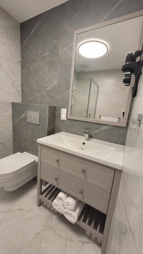 a bathroom with a sink and a toilet and a mirror at Hotel & Restauracja Wróblewscy in Karniewo