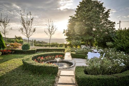 un jardin avec une fontaine, des buissons et des fleurs dans l'établissement Top - kuća za odmor, à Bukovik