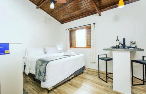 Un dormitorio blanco con una cama grande y una mesa en Chalé Mantiqueira, en Cunha