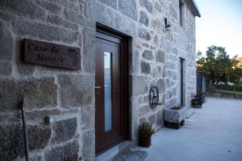 une porte menant à un bâtiment en pierre avec un panneau. dans l'établissement A CASA DA MOREIRA - Casa rural en Ponte Maceira, à A Coruña