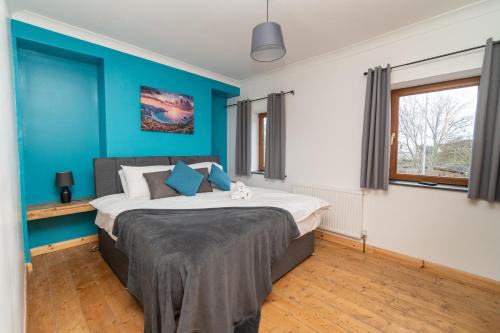 um quarto com uma cama grande e paredes azuis em Business friendly & Spacious 2BR home - Perfectly located for working in Swansea em Swansea