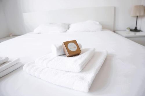 a clock on a pile of towels on a bed at Lovely Modern 1 BR apartment in Luxembourg