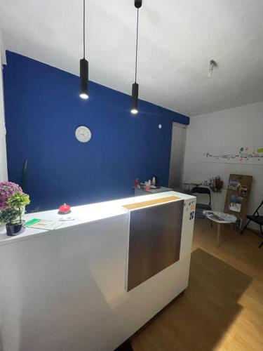a kitchen with a blue wall with a clock on it at Sky Hostel in Peje