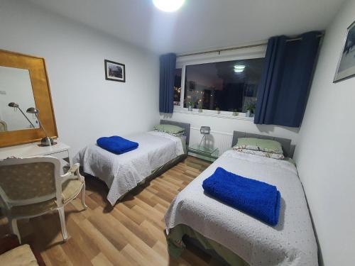 a bedroom with two beds and a window with blue pillows at Limehouse Guest House Central East London in London