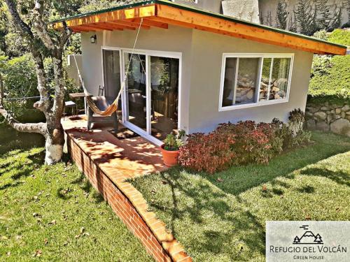 a small house with a hammock in the yard at Refugio del Volcan Casitas in San Pedro La Laguna