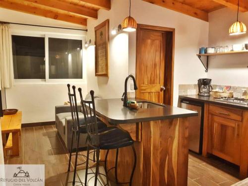 a kitchen with a sink and a counter with bar stools at Refugio del Volcan Casitas in San Pedro La Laguna
