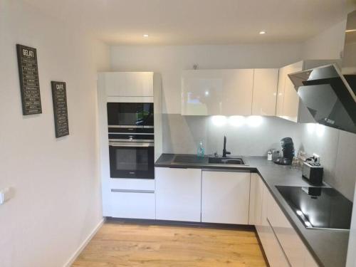 a kitchen with white cabinets and a black counter top at Kernsan. Souterrain-Wohnung 60qm mit Pool Blick in Krefeld