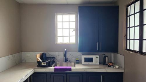 a kitchen with blue cabinets and a microwave at The Layover - 6 mins from the airport, Fully equipped for short and long stays in Kelly Village