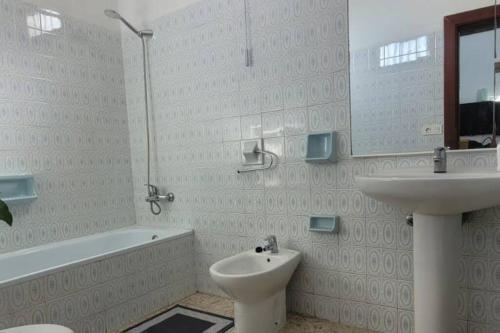 a bathroom with a sink and a toilet and a bath tub at Sabbia Suites Casa Malvasía in Mozaga