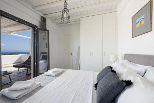 a white bedroom with a bed with a view of the ocean at Villa Isterni Paros in Isterni