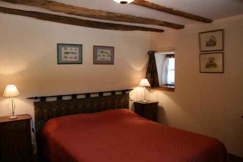 sypialnia z czerwonym łóżkiem i 2 lampami w obiekcie La Bergerie w mieście Beaulieu-sur-Dordogne