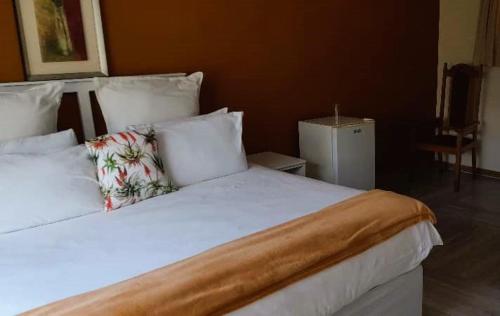 a bedroom with a large bed with white sheets and pillows at Tshulu Tsha Nabe B&B in Bulawayo