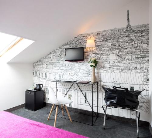 Cette chambre dispose d'un mur en briques, d'un bureau et d'une télévision. dans l'établissement Hôtel Victoria Châtelet, à Paris