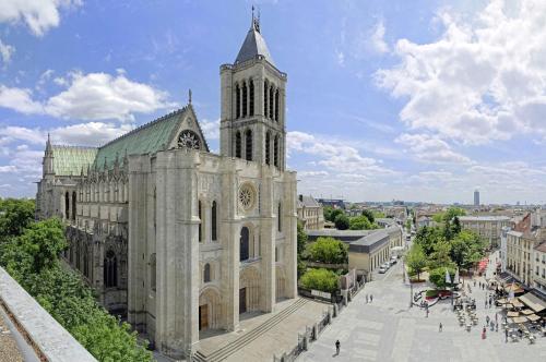 une grande cathédrale avec une tour d'horloge dans une ville dans l'établissement Le Duplex Paris Basilique Stade de France, à Saint-Denis