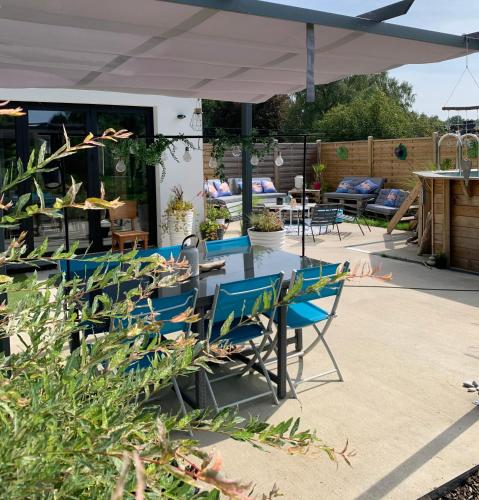 a patio with blue chairs and a glass table at Chez Isa in Faymonville