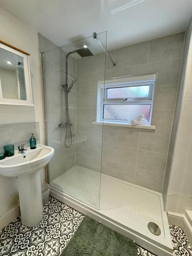 ein Bad mit einer Dusche und einem Waschbecken in der Unterkunft Rockcliffe Retreat, Stylish Coastal Apartment in Whitley Bay