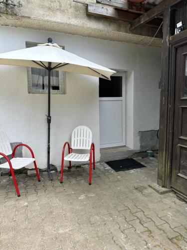 伊興豪森的住宿－Gemütliche Gäste Suite für ruhige Nächte. Zentral，庭院配有两把椅子和一把遮阳伞