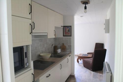 a kitchen with white cabinets and a chair in a room at Logement rénové proche forêt in Baud
