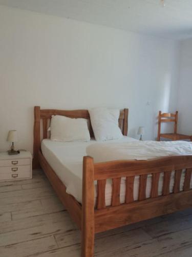 une chambre avec un lit en bois avec des draps blancs dans l'établissement Logement rénové proche forêt, à Baud