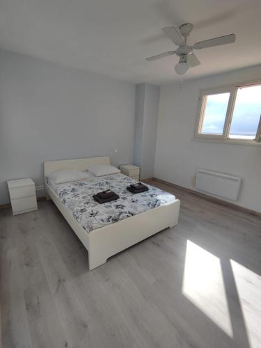 une chambre blanche avec un lit et un ventilateur de plafond dans l'établissement La perle de Sète Maison bord de l étang Animaux bienvenus Sur demande, à Sète