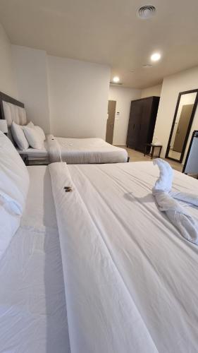 two beds in a hotel room with white sheets at Mizirawi Historic Hotel in Ramallah